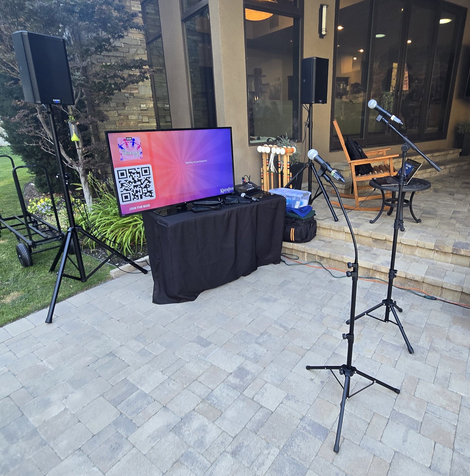 Karaoke speakers, microphones, and screen set up for an outdoor event